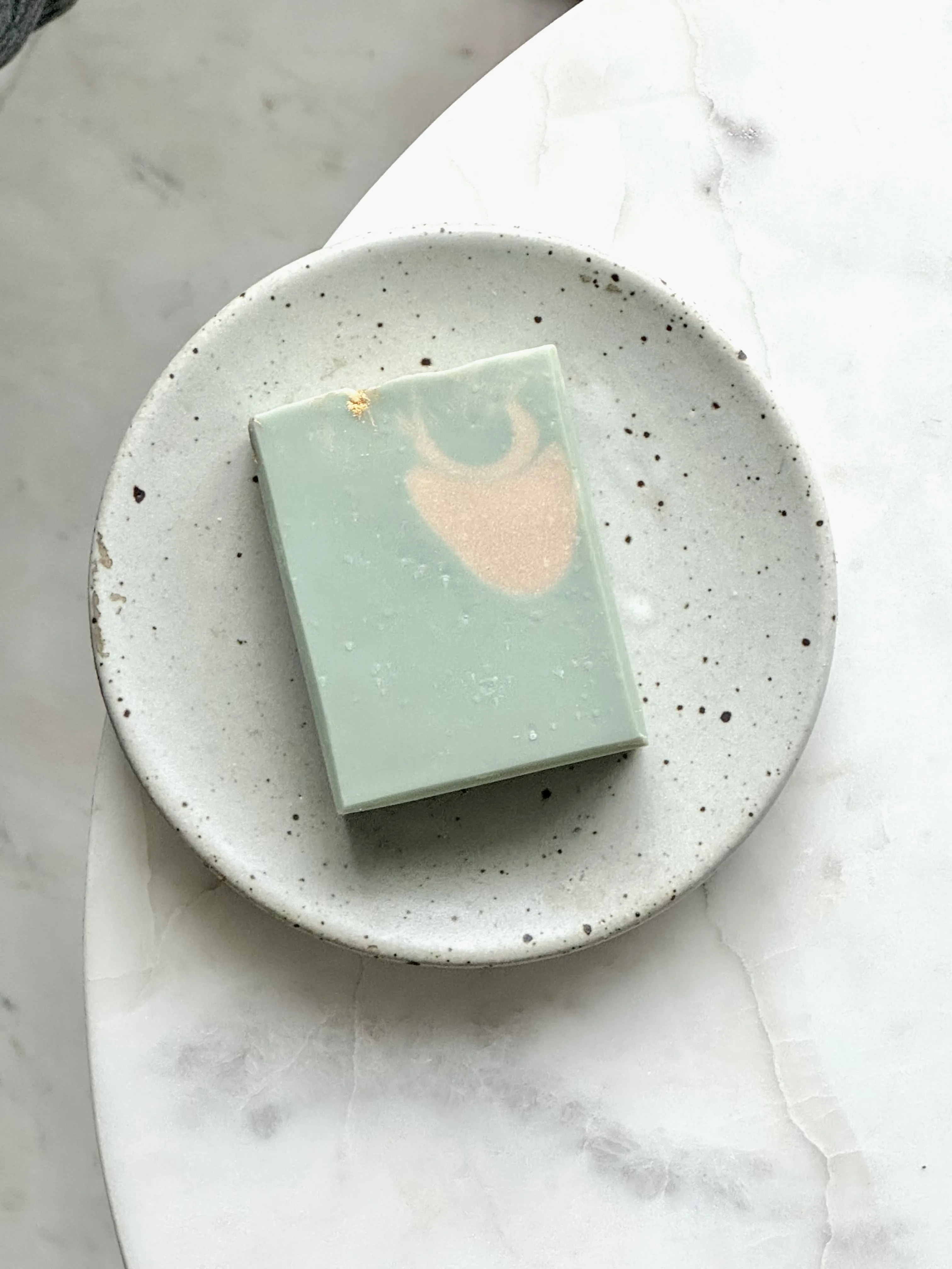 green with creamy white bar soap on grey soap dish