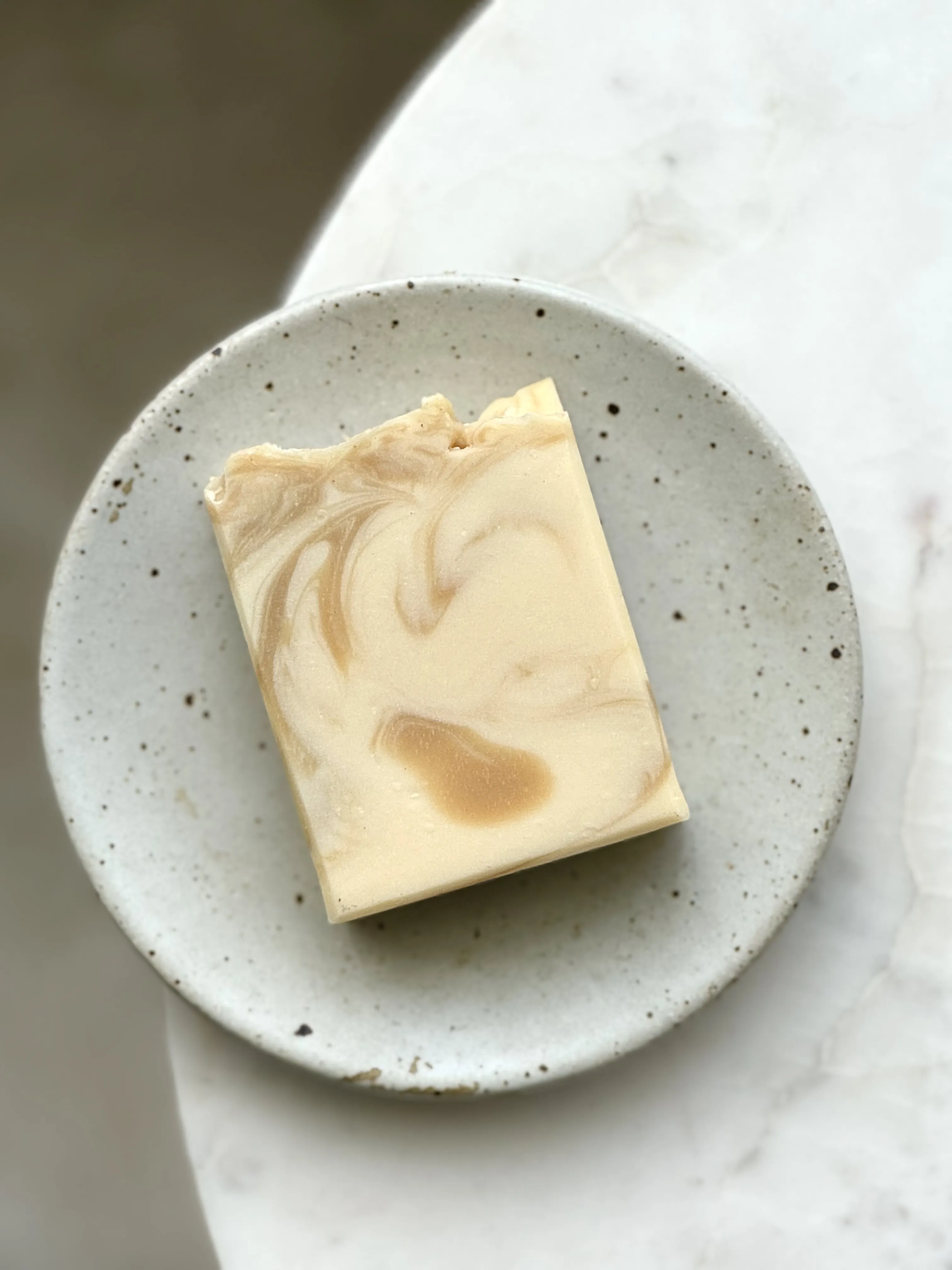 creamy white and brown bar soap on grey soap dish 