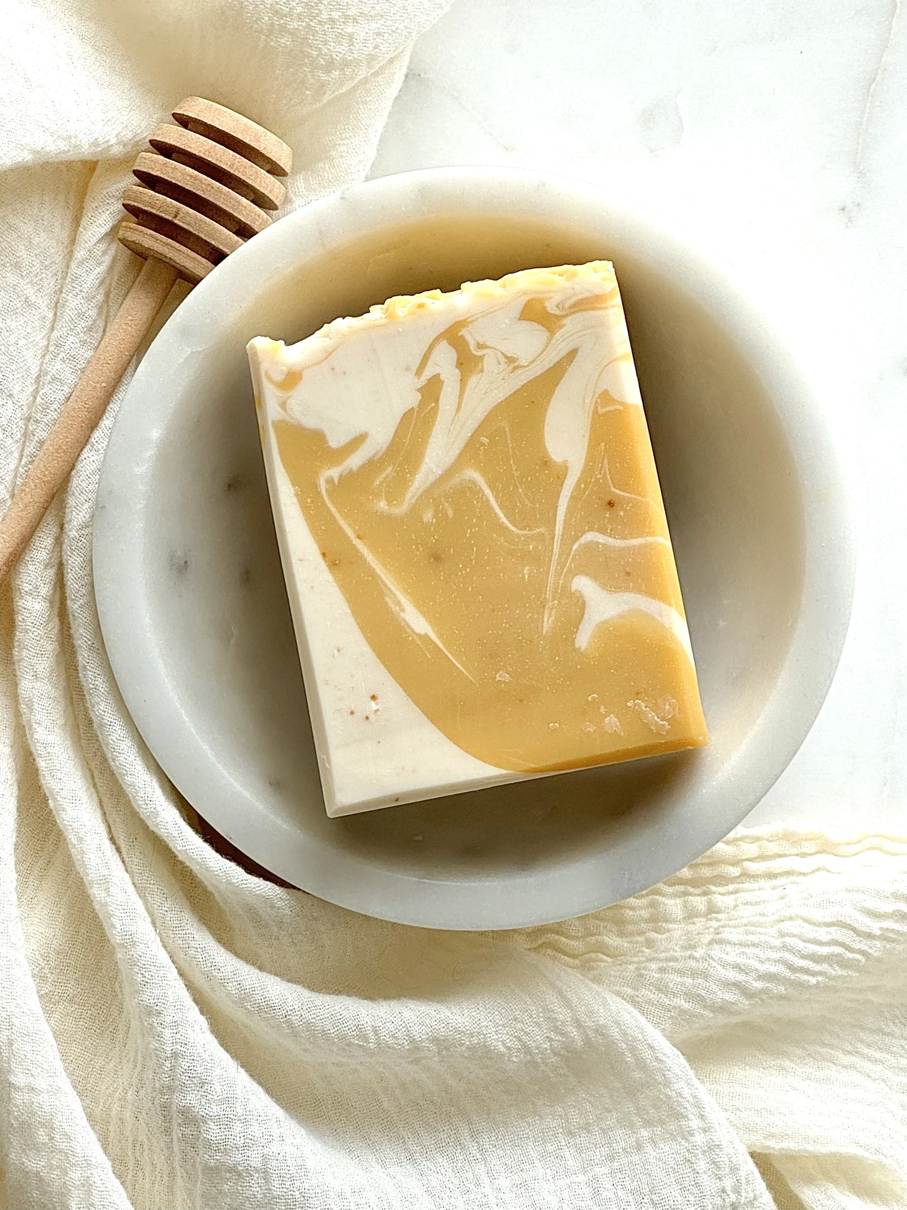 Image of white and dark yellow bar soap in a marble bowl