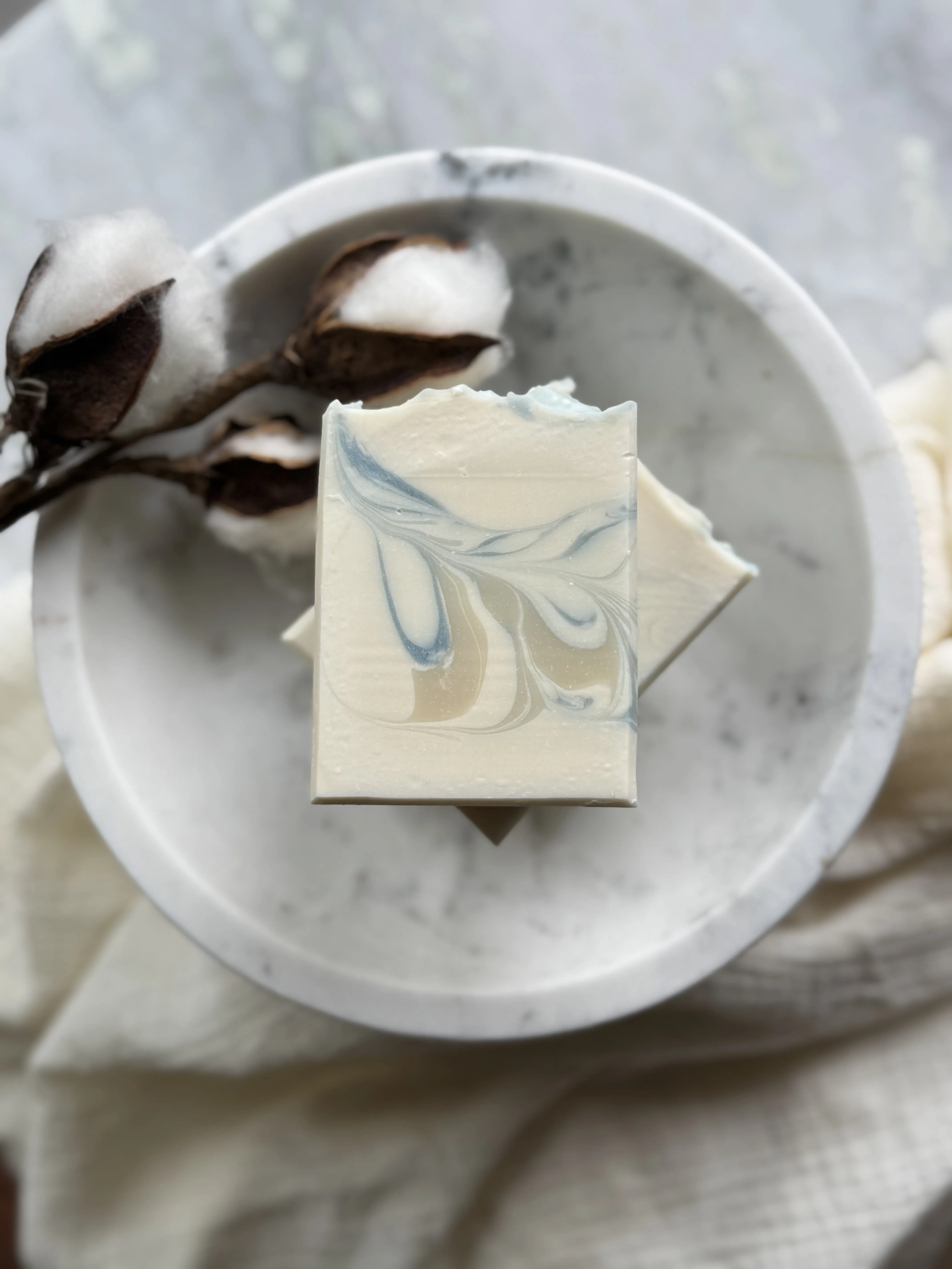Image of white bar soap with pastel blue and ecru swirls